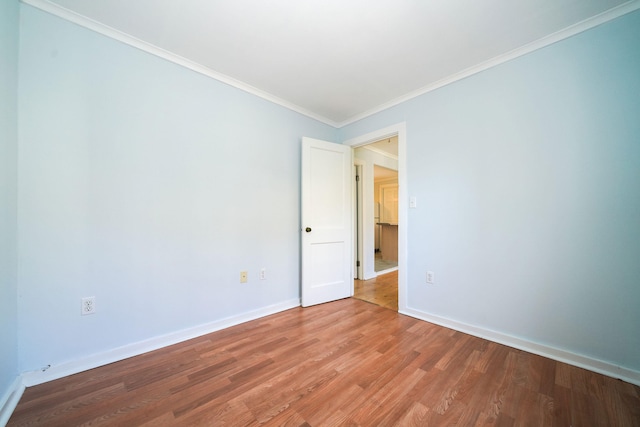 unfurnished room featuring light wood finished floors, baseboards, and ornamental molding