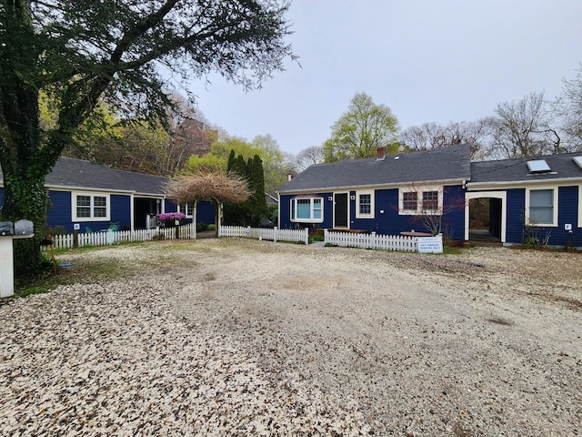 view of front facade featuring driveway, a chimney, and fence private yard