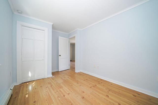 unfurnished bedroom featuring baseboards, crown molding, light wood-type flooring, a baseboard heating unit, and a closet