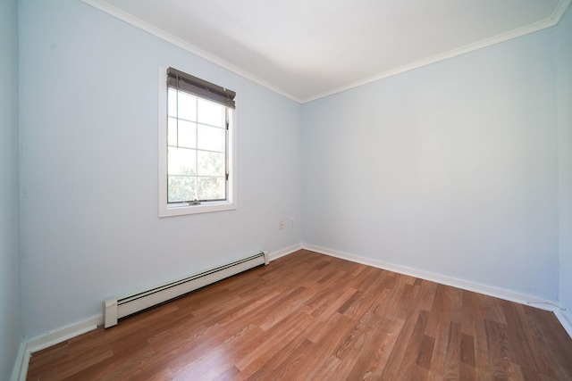 spare room featuring baseboards, baseboard heating, wood finished floors, and crown molding