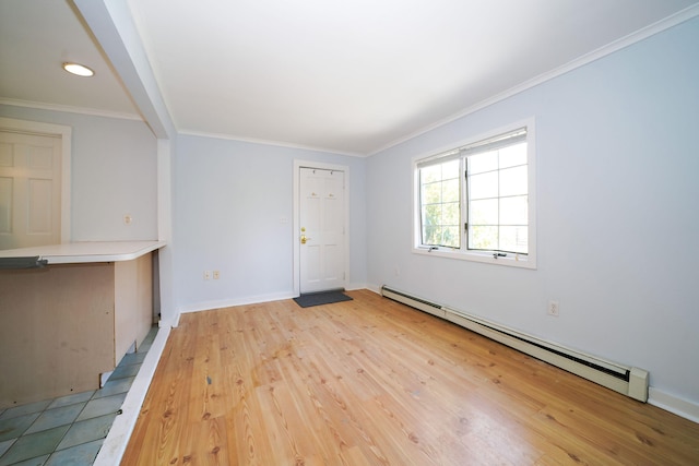 spare room featuring a baseboard heating unit, ornamental molding, light wood finished floors, and baseboards