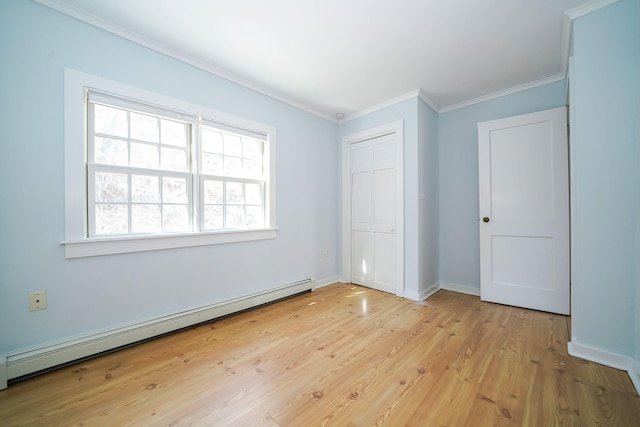 unfurnished bedroom with baseboards, light wood-style floors, baseboard heating, a closet, and crown molding