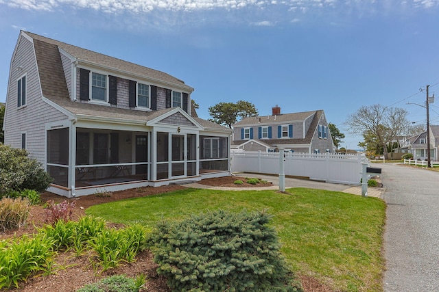 29 Hiawatha Rd, Harwich Port, MA 02646 - rear view of house featuring fence, a gambrel roof, a sunroom, a shingled roof, and a yard