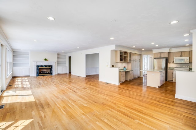 unfurnished living room with built in features, baseboards, recessed lighting, light wood-style flooring, and a premium fireplace