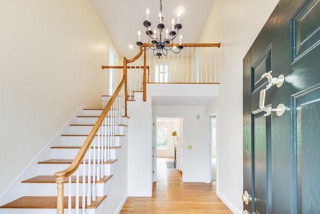entrance foyer featuring stairway, a high ceiling, an inviting chandelier, and wood finished floors