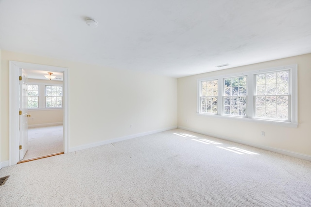 empty room with carpet flooring, baseboards, and visible vents