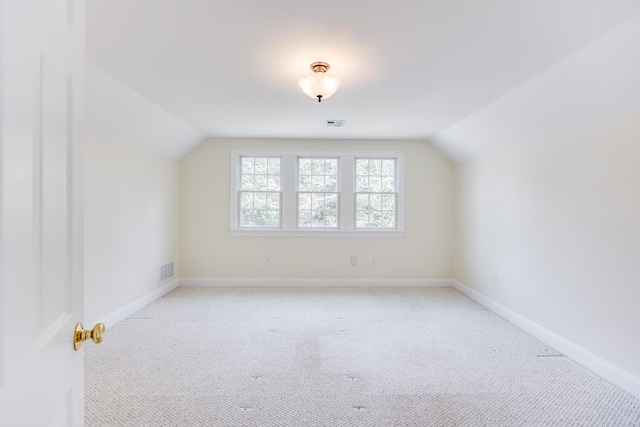 additional living space with visible vents, baseboards, vaulted ceiling, and light colored carpet