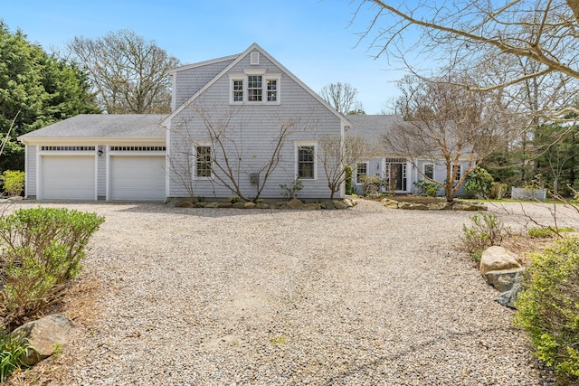 view of front of house featuring an attached garage, roof with shingles, and gravel driveway