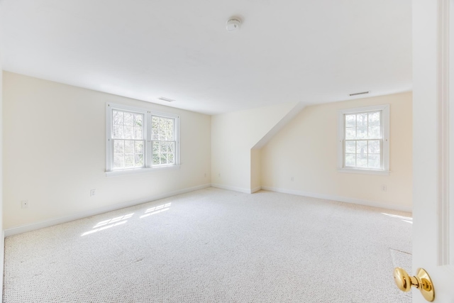 additional living space with baseboards, plenty of natural light, and light carpet