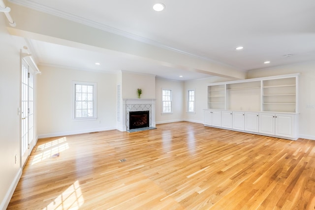 unfurnished living room with crown molding, a wealth of natural light, and light wood-style floors