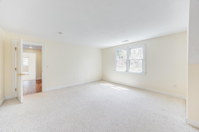 carpeted empty room with baseboards, visible vents, and plenty of natural light