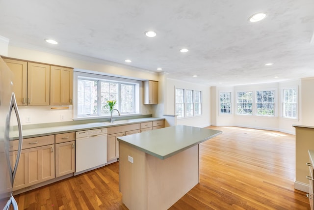 kitchen featuring crown molding, white dishwasher, a sink, and a center island