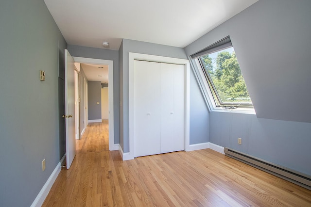 unfurnished bedroom with a closet, light wood-type flooring, and baseboard heating