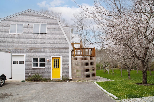 view of side of property featuring a deck, a yard, and a garage