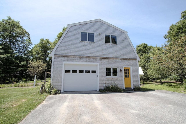 view of front of house featuring a garage, an outbuilding, and a front lawn