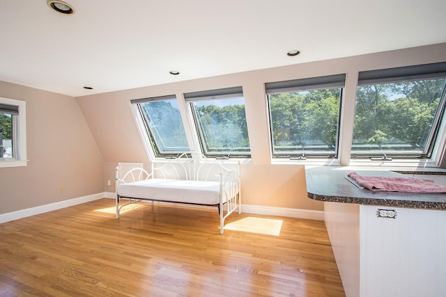 unfurnished room with light hardwood / wood-style floors and lofted ceiling with skylight