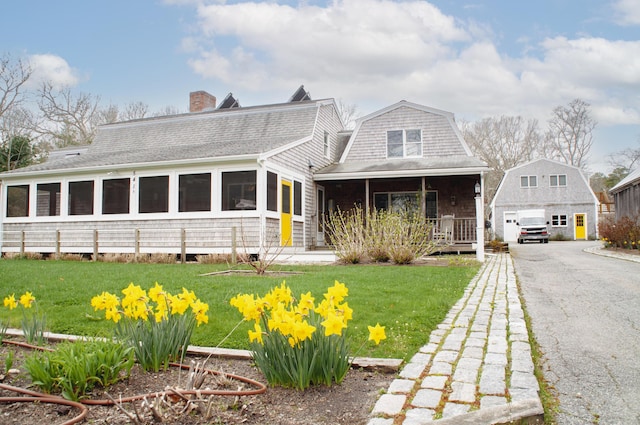 view of front facade featuring covered porch, a front yard, and a garage