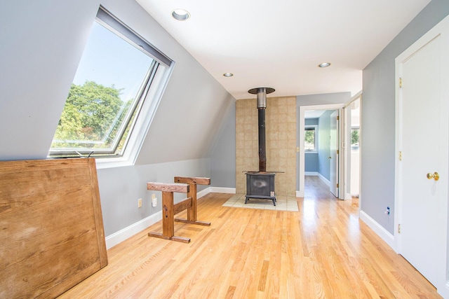 living room featuring light hardwood / wood-style floors, a wood stove, and vaulted ceiling