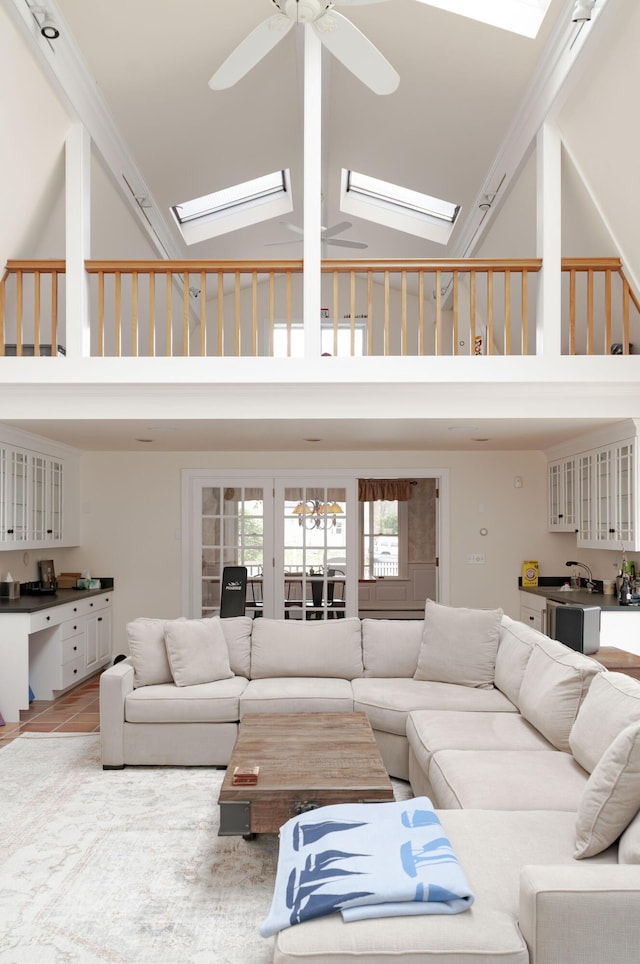 tiled living room featuring sink, a skylight, high vaulted ceiling, and ceiling fan