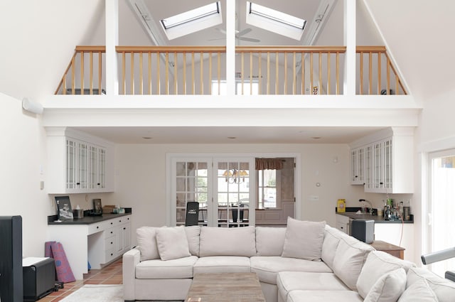 tiled living room with a skylight, high vaulted ceiling, ceiling fan, and french doors