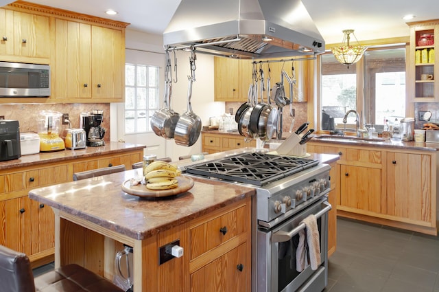 kitchen with sink, island exhaust hood, light stone counters, a kitchen island, and stainless steel appliances