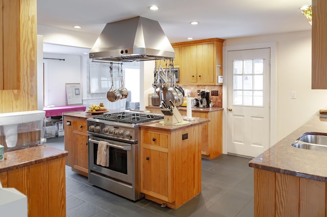 kitchen with dark tile patterned floors, a kitchen island, island exhaust hood, tasteful backsplash, and stainless steel range with gas stovetop