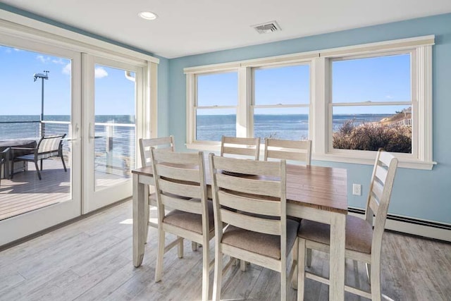 dining area with a water view, light wood finished floors, visible vents, and recessed lighting