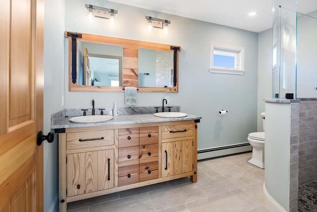 full bath featuring double vanity, baseboard heating, a sink, and toilet