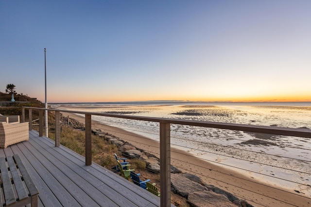 wooden deck featuring a water view and a beach view