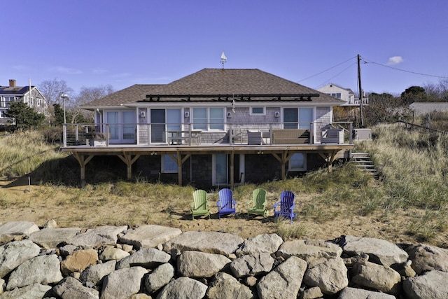 back of house featuring a shingled roof and a wooden deck