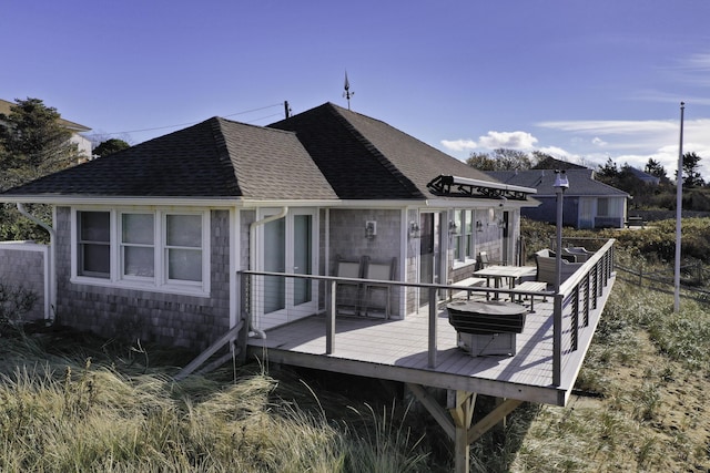 back of property featuring roof with shingles and a deck