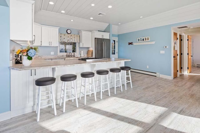 kitchen with a breakfast bar, high end refrigerator, a baseboard heating unit, and light countertops