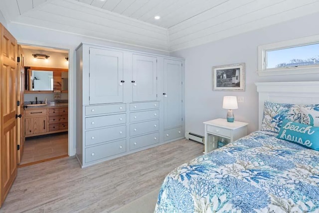 bedroom featuring light wood-type flooring, a closet, connected bathroom, and baseboard heating