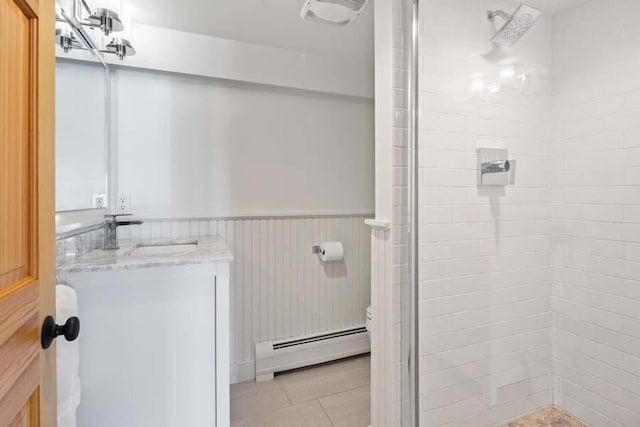 full bath featuring a wainscoted wall, a baseboard radiator, toilet, a stall shower, and vanity