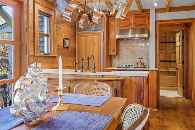 260 Bradford St, Provincetown, MA 02657 - kitchen featuring exhaust hood, wood walls, paneled fridge, light countertops, and tasteful backsplash