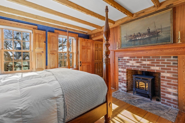 260 Bradford St, Provincetown, MA 02657 - bedroom featuring a wood stove, hardwood / wood-style floors, beamed ceiling, and wooden walls