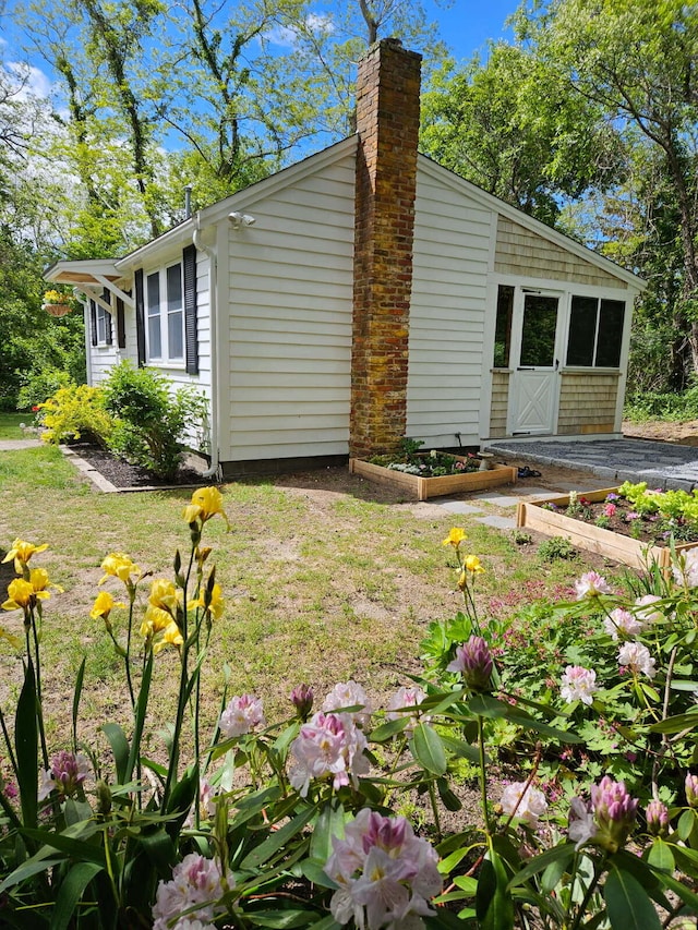 1079 State Hwy Unit 14, Eastham, MA 02642 - view of home's exterior featuring a vegetable garden and a chimney