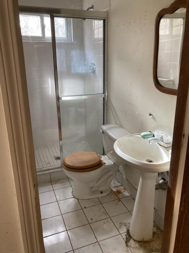 bathroom with tile patterned floors, toilet, and a shower with shower door