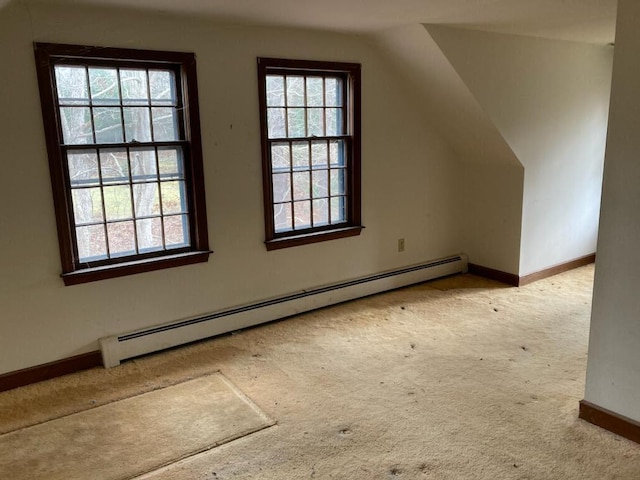 additional living space with a baseboard heating unit, vaulted ceiling, and light colored carpet