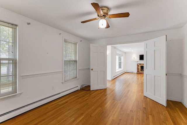 100 Potonumecot Rd, Chatham, MA 02633 - empty room with baseboard heating, light wood-style floors, a fireplace, and ceiling fan