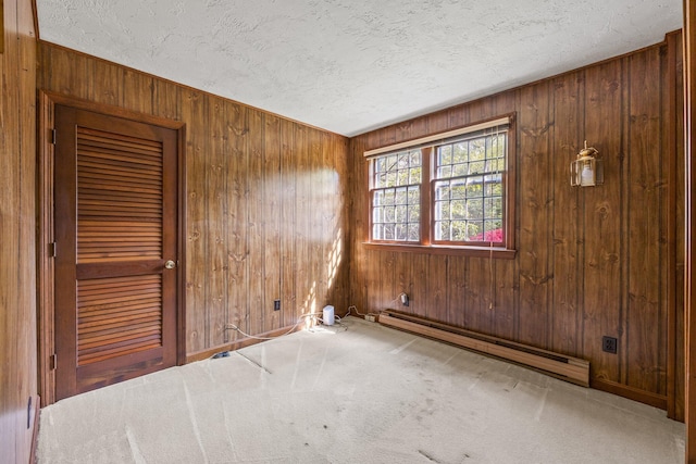154 Cotuit Bay Dr, Cotuit, MA 02635 - carpeted empty room with a baseboard heating unit, a textured ceiling, and wood walls