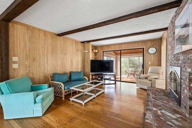 154 Cotuit Bay Dr, Cotuit, MA 02635 - living room with wooden walls, beamed ceiling, a brick fireplace, hardwood / wood-style floors, and a textured ceiling