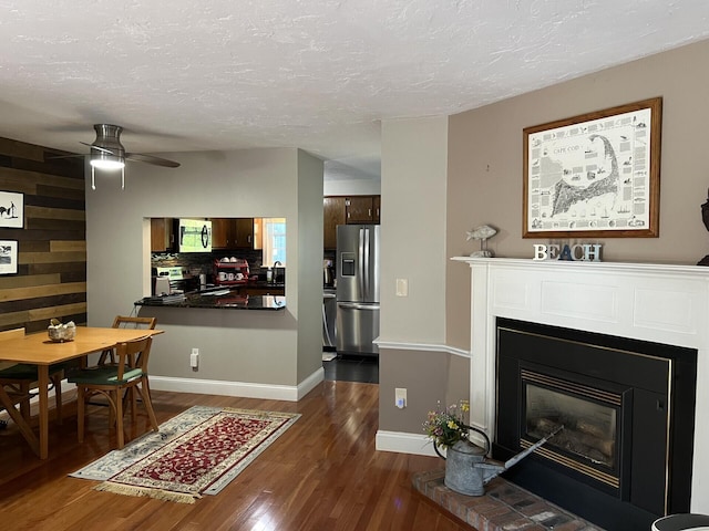 living room featuring sink, ceiling fan, wood walls, and dark wood-type flooring