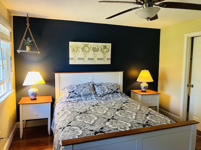 bedroom with baseboard heating, multiple windows, ceiling fan, and dark hardwood / wood-style flooring