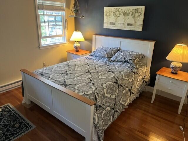 bedroom with dark wood-type flooring and baseboard heating