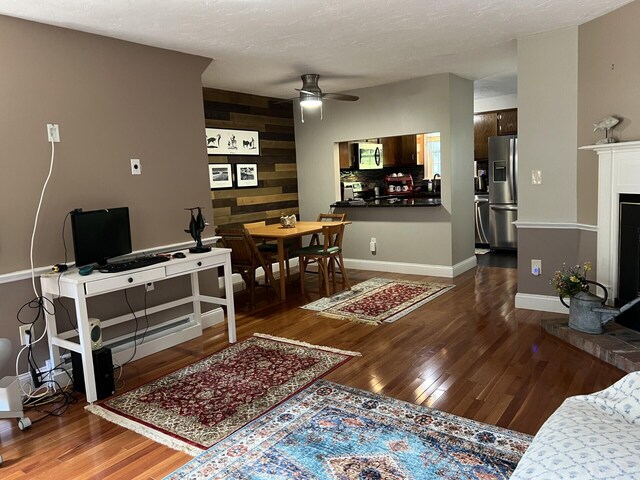 living room with dark wood-type flooring, wooden walls, and ceiling fan