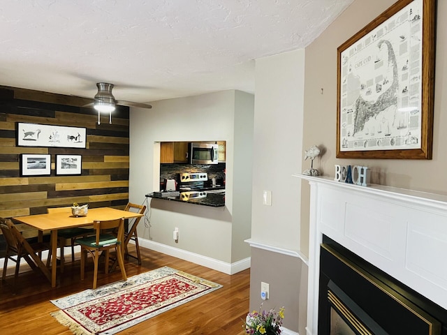 dining area with ceiling fan, wood walls, and hardwood / wood-style floors