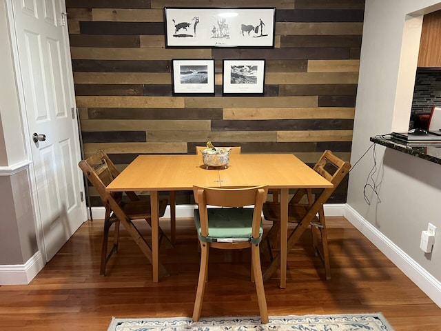 dining area featuring wood walls and dark wood-type flooring