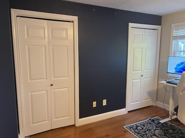 bedroom with hardwood / wood-style flooring and multiple closets