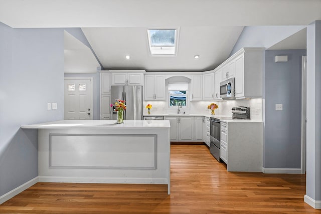 97 Great Western Rd, Harwich, MA 02645 - kitchen with decorative backsplash, a peninsula, white cabinets, a sink, and appliances with stainless steel finishes